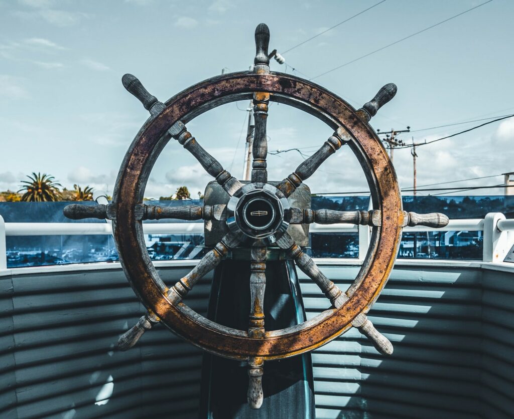 Closeup image of an old ship's wheel, looking out the front of the boat.