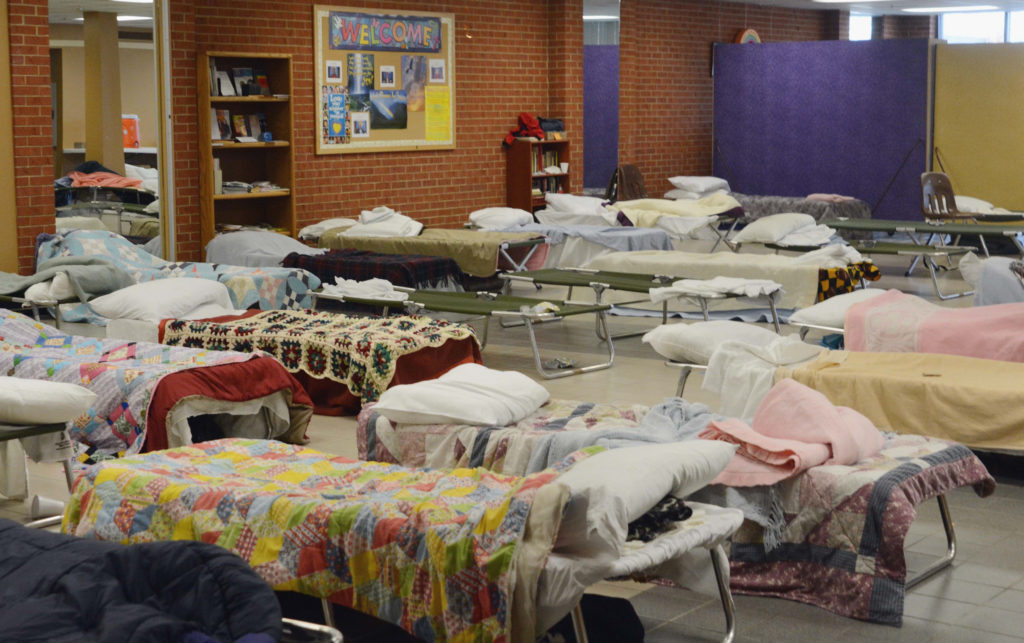 Photograph of empty cots in homeless shelter