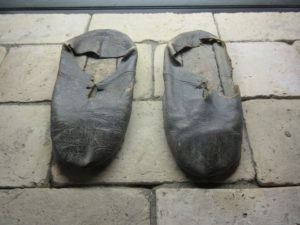 Worn leather shoes resting on brick floor