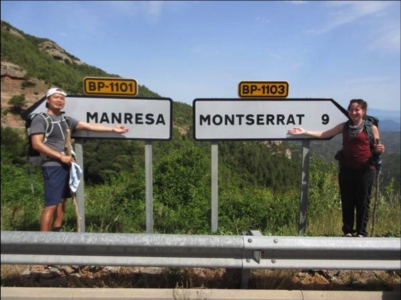 Pham and Barush stand by roadsigns pointing opposite ways to Manresa and Montserrat