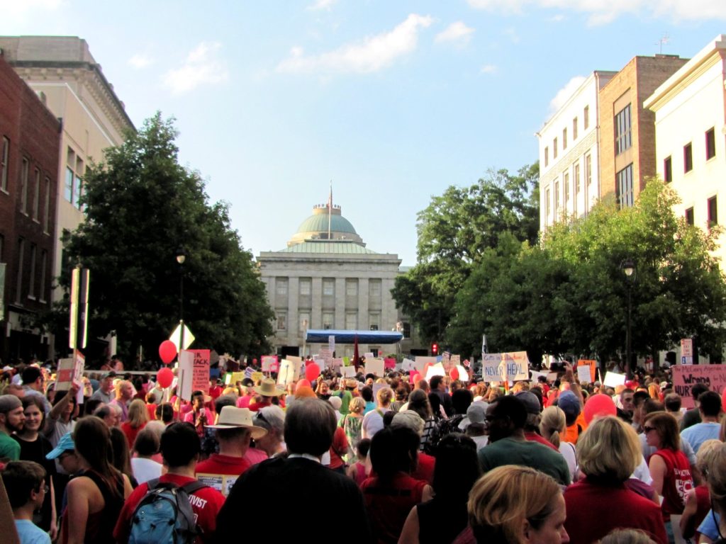A large crowd of protesters stands in front of the North Carolina capitol